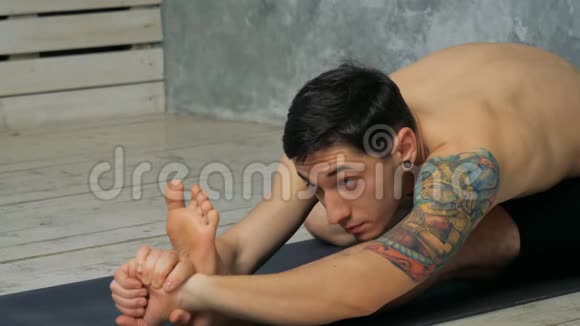 男人在健身房练习瑜伽坐在帕西莫塔纳锻炼坐着向前弯曲的姿势视频的预览图
