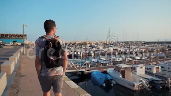 阳光明媚的早晨男游客正在海上码头和游艇散步视频的预览图