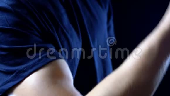 在黑色背景和黑色T恤上一个年轻人手上的二头肌视频的预览图