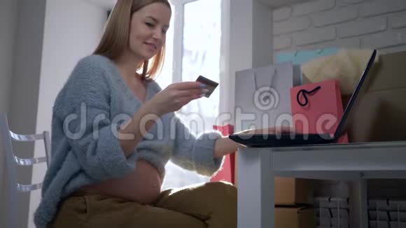 网上购物年轻的产妇用塑料卡使用笔记本电脑上网付款视频的预览图