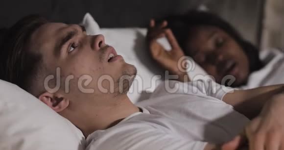 多民族夫妇躺在床上男人在床上遭受伴侣的鼾声夫妻生活方式和人视频的预览图