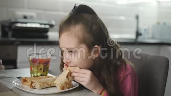 厨房里的小女孩吃肉馅卷饼喝茶视频的预览图