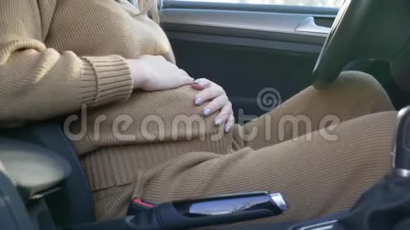孕妇在车上照顾孕妇抚摸腹部并在驾驶车辆前系上安全带视频的预览图