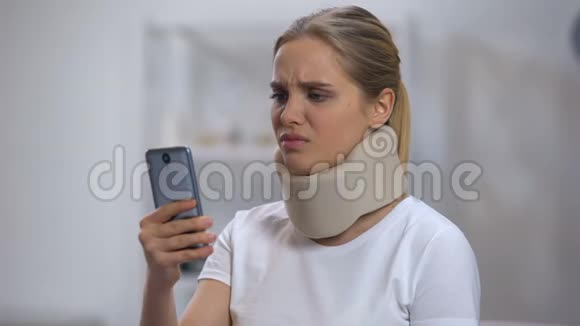戴泡沫颈项圈的女人在手机上读短信感觉脖子疼视频的预览图