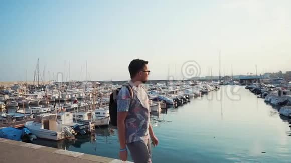 快乐的年轻人在夏天和停泊的游艇在码头上独自行走视频的预览图