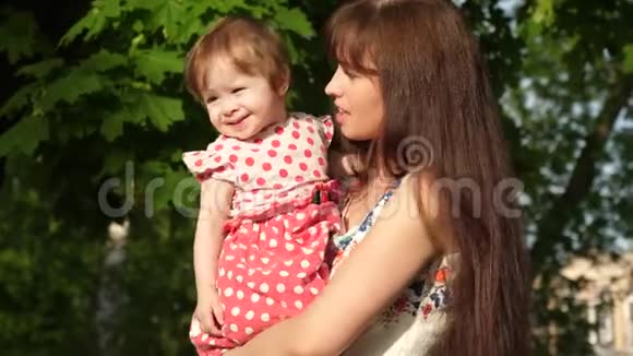 快乐的妈妈抱着一个漂亮的女儿妈妈带着一个孩子在夏园散步视频的预览图