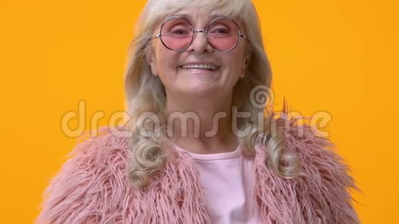 时髦的祖母穿着粉红色的毛皮和现代眼镜送空气亲吻调情视频的预览图