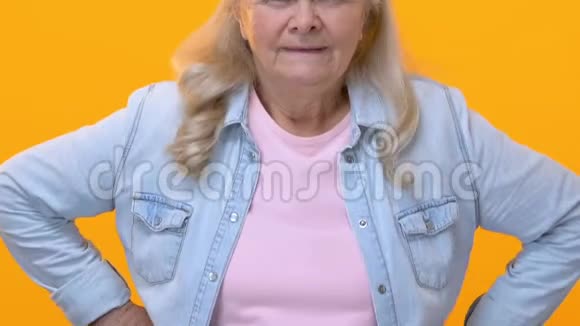 失望的奶奶愤怒地看着黄色的背景老一代指责视频的预览图