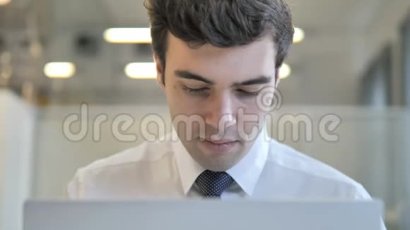 年轻商人在笔记本电脑上工作正面视图视频的预览图