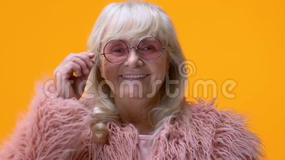 时尚的老妇人摘下粉红色的眼镜对着镜头微笑幸福视频的预览图
