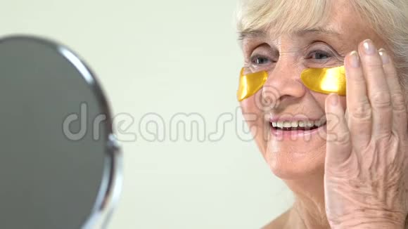 老年女性面部有抗衰老水凝胶眼贴照镜视频的预览图