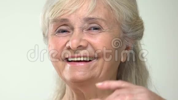 快乐老年女性抚摸光滑的面部肌肤保湿霜效果护理视频的预览图