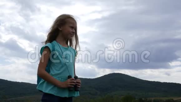 一个年轻的女孩站在群山和多云的天空的背景下寻找方向视频的预览图