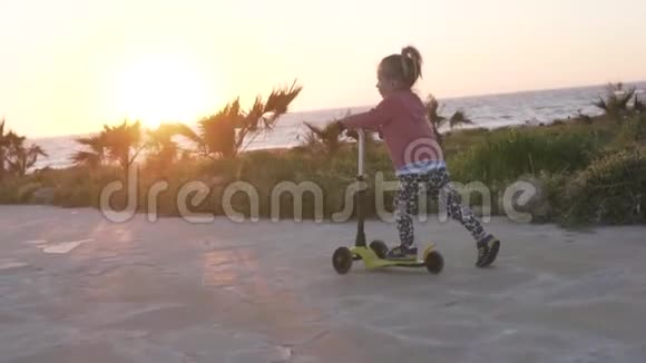 一个小女孩骑着摩托车在海边的路上视频的预览图