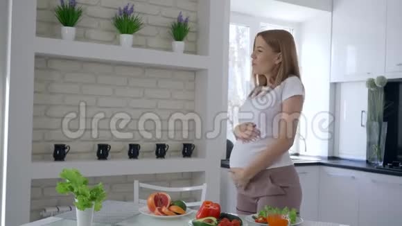 孕期的维生素食品可爱的未来妈妈在早午餐时在厨房里用新鲜蔬菜跳舞视频的预览图