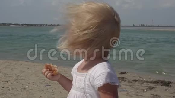 小女孩在海滩上吃早餐海岸上的一个孩子快乐快乐的孩子视频的预览图