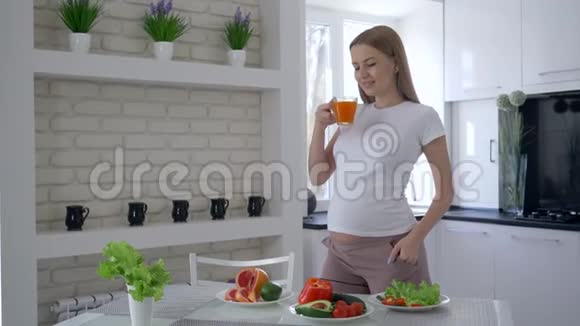 幸福的孕妇大肚子在健康的午餐中喝新鲜果汁在公寓里的美食视频的预览图