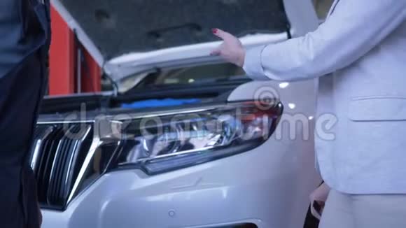 女消费者为汽车修理工提供汽车钥匙并在服务站握手视频的预览图