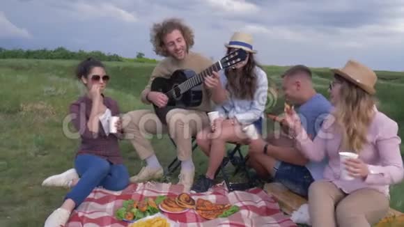 在大自然中休息欢乐的男女朋友在露天野餐聚会上玩玩吉他视频的预览图