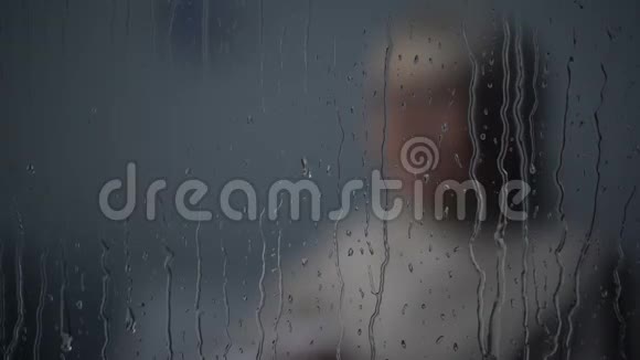沮丧的老年妇女在雨天的黑暗房间里哭泣孤独视频的预览图