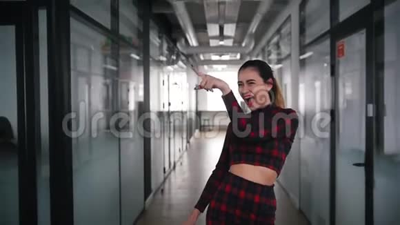 一位兴奋的商务女性在办公室走廊里跳舞指着她的同事微笑视频的预览图