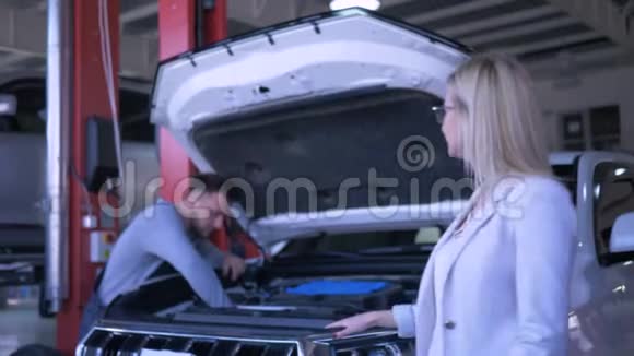 服务站幸福女士消费车主肖像在工作过程中机械师修理车辆开放视频的预览图