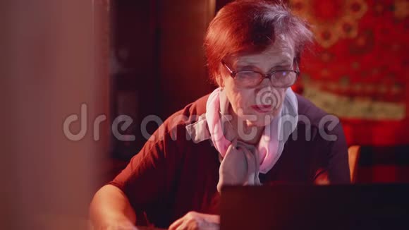 戴眼镜的老妇人在家里看手提电脑显示器视频的预览图