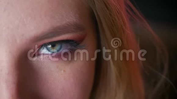 神秘迷人的女性蓝色眼睛化妆粉红色阴影和金色眼线与黑暗的背景视频的预览图