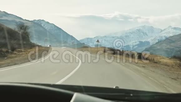 从挡风玻璃上看一辆汽车在美丽的山脉和背景下沿着一条山路行驶视频的预览图