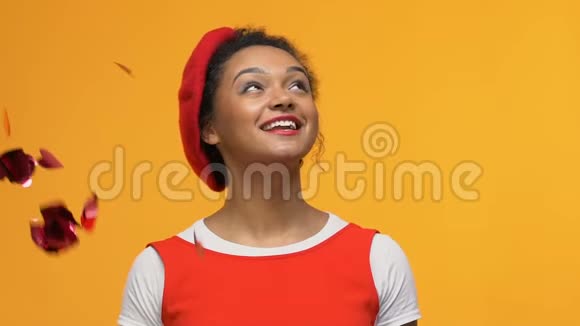 快乐的年轻女子站在黄色背景下的纸屑雨浪漫的心情视频的预览图