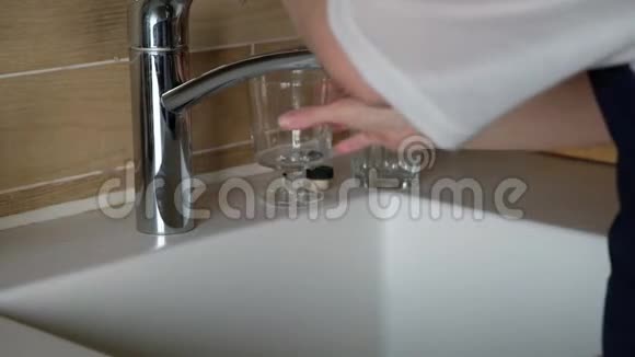 关闭女性手打开水龙头在厨房玻璃中倒水视频的预览图
