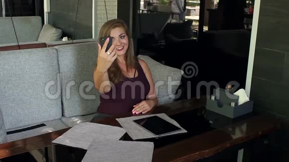 一个体重超标的年轻女人坐在咖啡馆里自拍视频的预览图