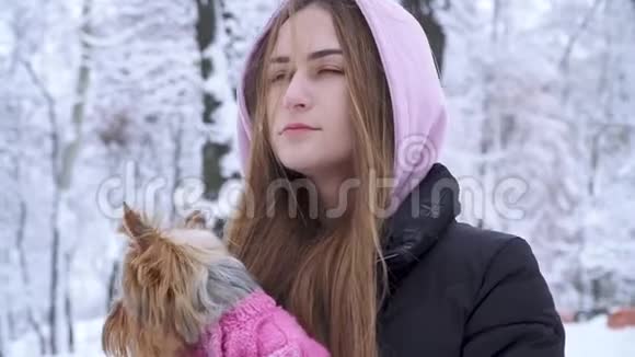 一位留着长发的可爱少女抱着一只穿着羊毛衫的约克郡猎犬双手抱着狗视频的预览图