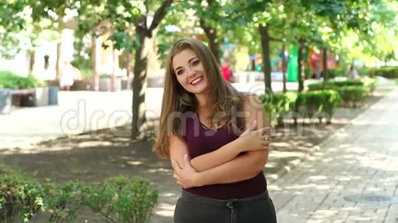 女孩模特超重长发在阳光明媚的夏季城市公园摆姿势视频的预览图