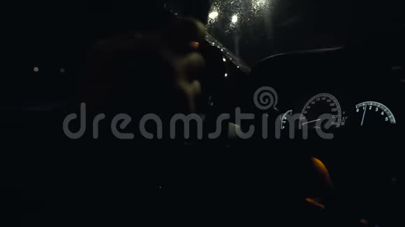 男子在雨夜驾驶汽车和方向盘汽车控制面板上的灯视频的预览图