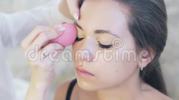 特写裁剪框的年轻女子来到化妆处化妆师把上眼皮上的遮瑕膏解释成视频的预览图