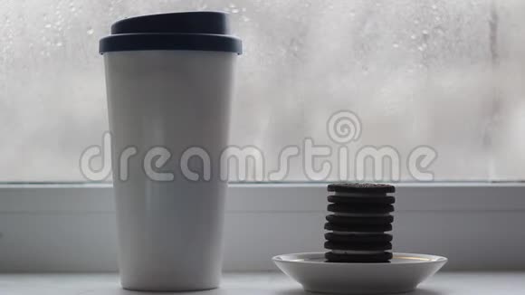 窗台上有一个带咖啡架的盖子的杯子盘子旁边有一堆饼干视频的预览图