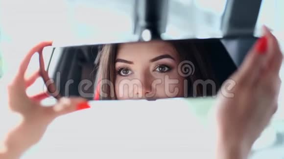 优雅的女人在车镜里修头发视频的预览图