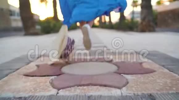 一个穿着漂亮蓝色裙子的女人的腿沿着棕榈大道跑帽子掉在地上视频的预览图