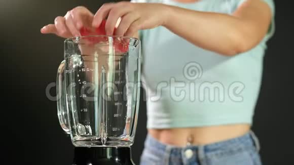 一个年轻的女人把西红柿放进搅拌机里加一些水关门视频的预览图