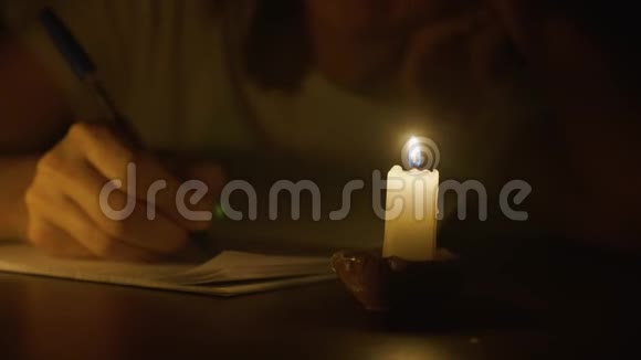 在昏暗的房间里年轻女子正在烛光下用笔写字视频的预览图