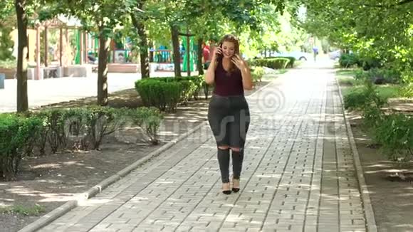 一个体重超标的年轻女孩在公园里散步打电话视频的预览图