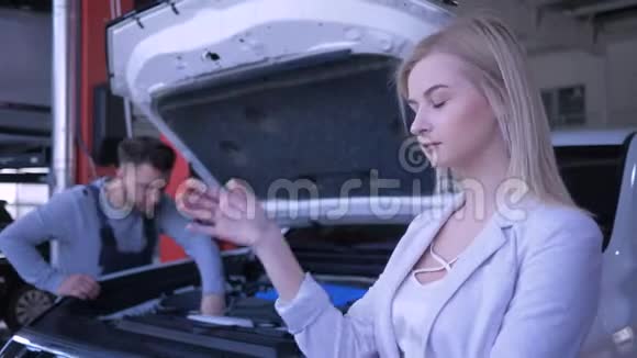 一位伤心的客户妇女为加油站的机械师修理的敞篷破车而难过视频的预览图
