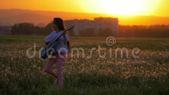 美丽的少年女孩在城市的背景下在户外演奏音乐夕阳的余晖下更有趣的鬼脸剪影视频的预览图