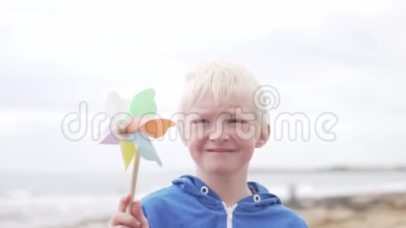 金发男孩拿着一个风车玩具视频的预览图