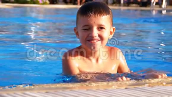 快乐的男孩在蓝水池里玩慢动作视频的预览图