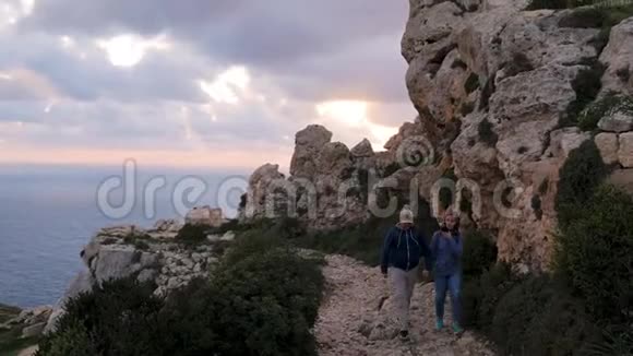 两名游客沿着岩石靠海散步岩石表面旅游旅游家庭令人惊叹的环境绿色视频的预览图