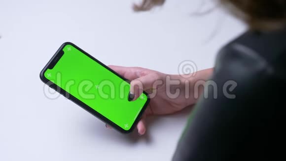 特写后景拍摄女性手在手机上发短信白色的办公室里有绿色的彩色屏幕视频的预览图