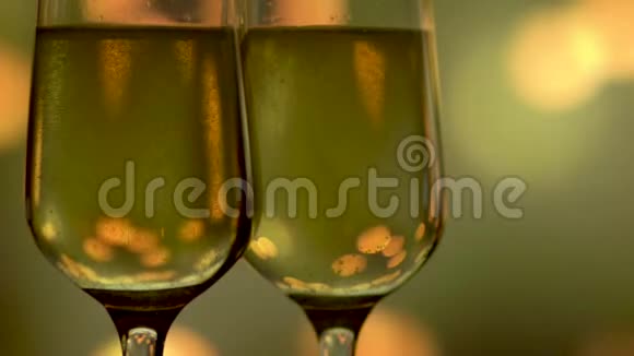 两杯香槟在抽象的金色闪烁背景上闪闪发光视频的预览图