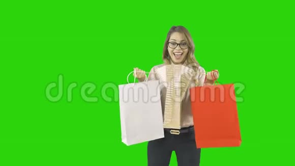 年轻漂亮的女人拿着礼品袋看着里面在一个孤立的背景上热情地微笑着视频的预览图